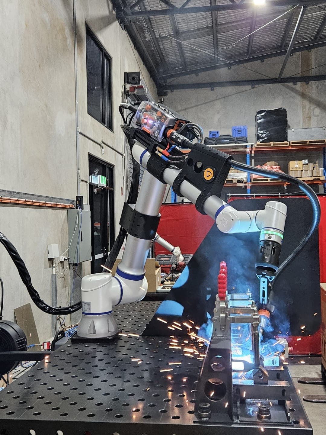 Cobot welder mid-arc with vertical spark spray